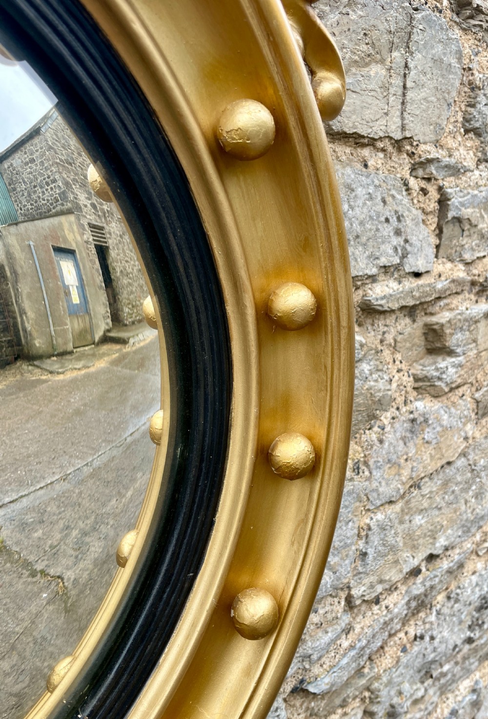 An ornate circular giltwood convex mirror featuring a carved eagle top cresting, acanthus leaf scrolling, ball mouldings, and an ebonised inner slip frame. View VI