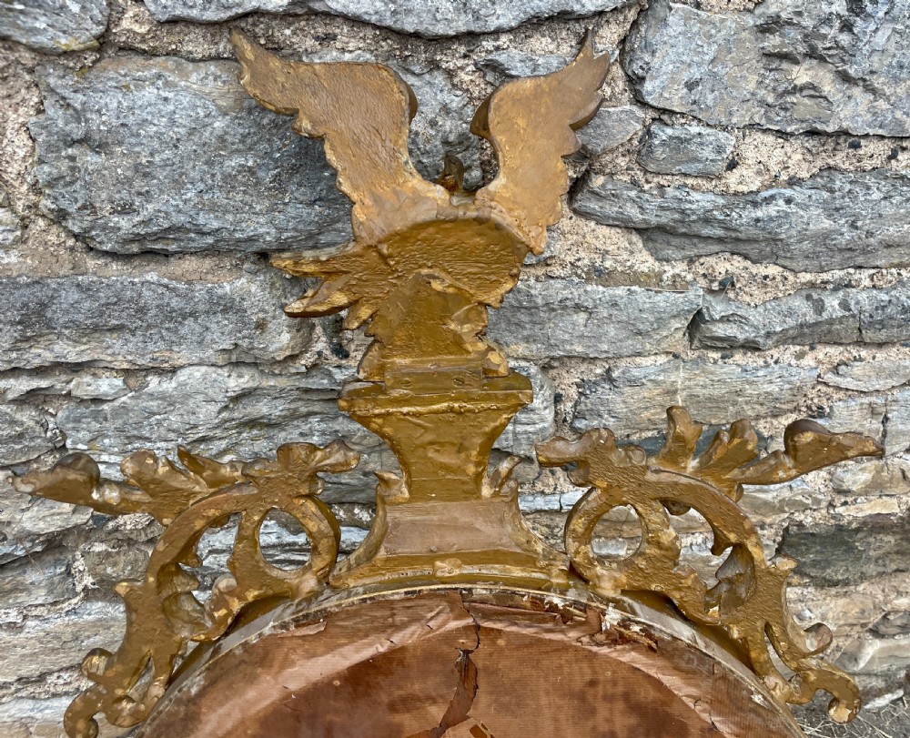An ornate circular giltwood convex mirror featuring a carved eagle top cresting, acanthus leaf scrolling, ball mouldings, and an ebonised inner slip frame. View XII