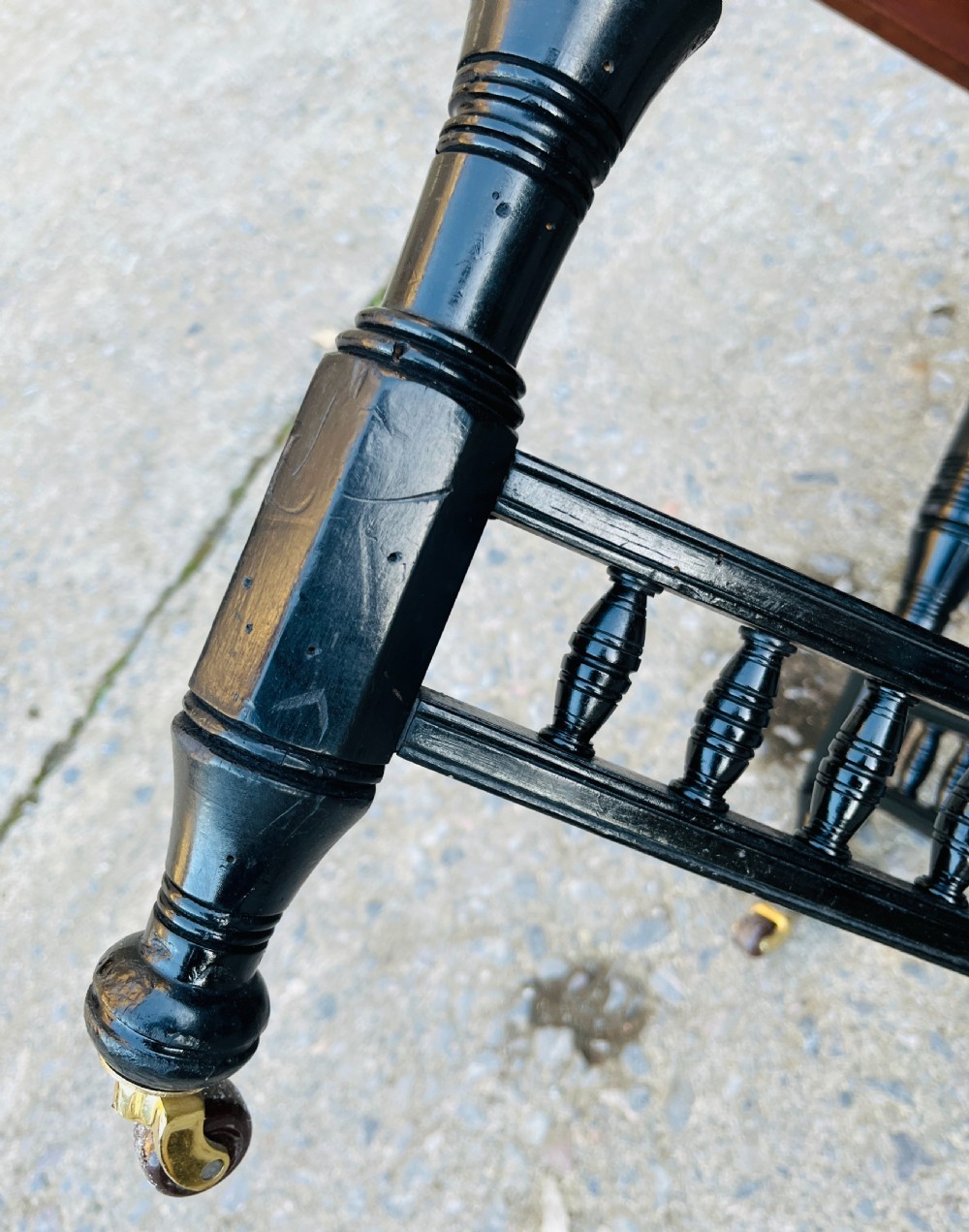 An octagonal ebonised Aesthetic Movement centre table featuring turned legs, brass castors, and a spindle X-frame stretcher. View XIV