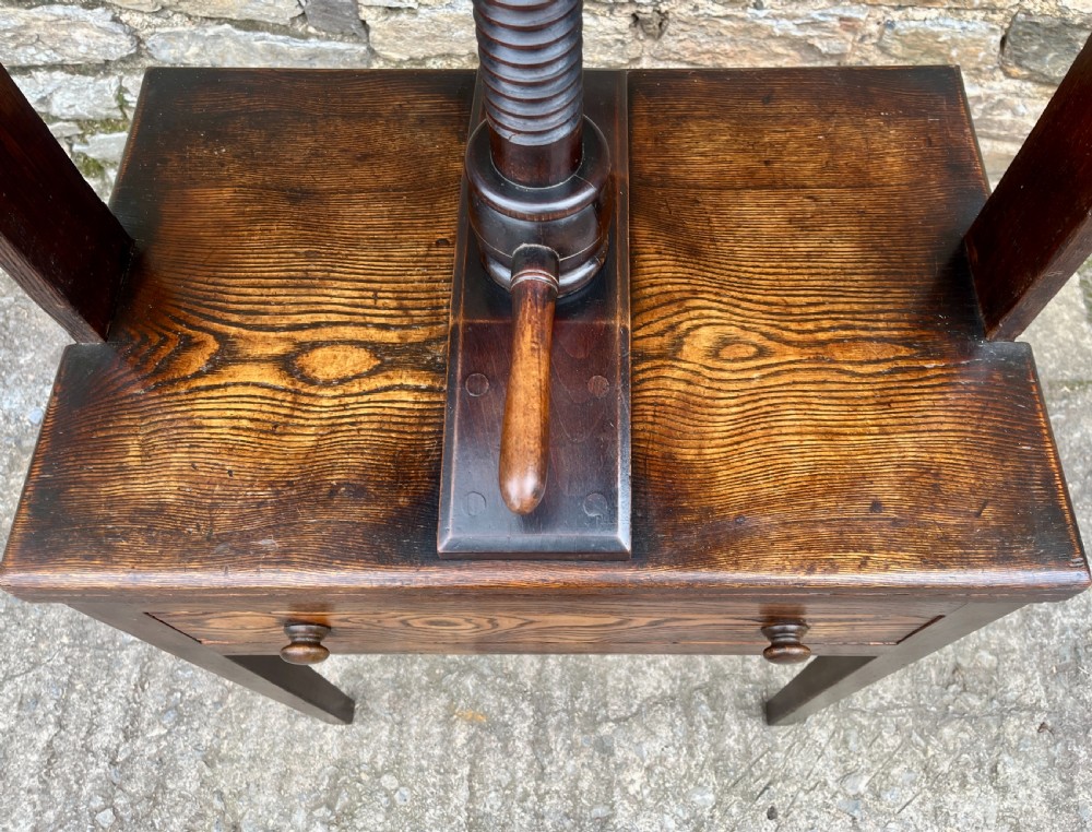 An antique oak and elm book press table featuring a central turned wooden screw mechanism above a single drawer with two round knobs. View IX