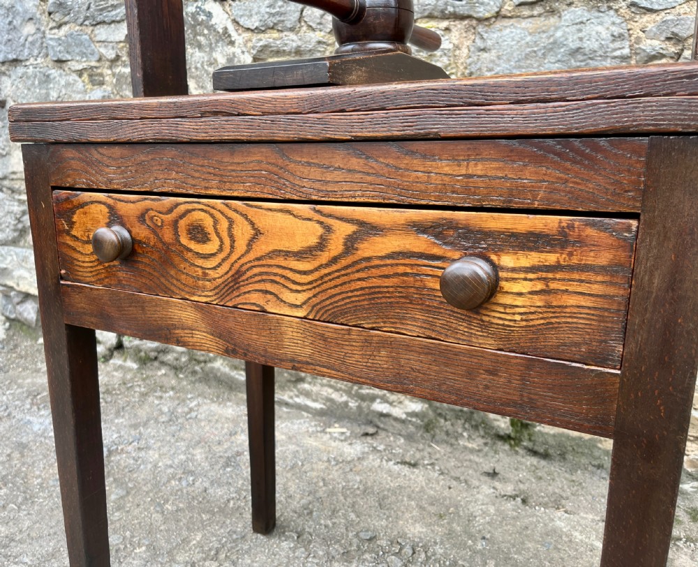 An antique oak and elm book press table featuring a central turned wooden screw mechanism above a single drawer with two round knobs. View XI