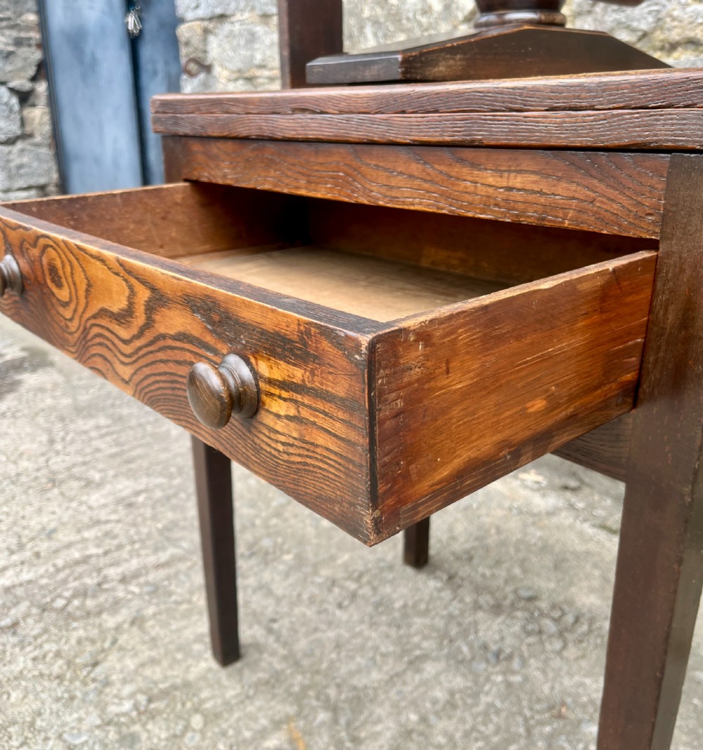 An antique oak and elm book press table featuring a central turned wooden screw mechanism above a single drawer with two round knobs. View XIII