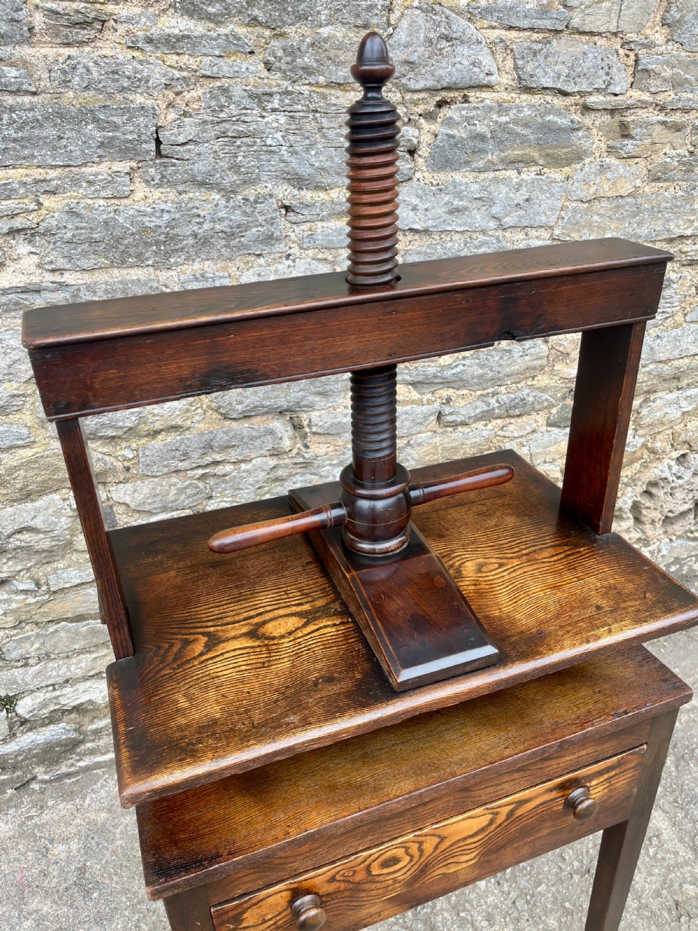 An antique oak and elm book press table featuring a central turned wooden screw mechanism above a single drawer with two round knobs. View XIV