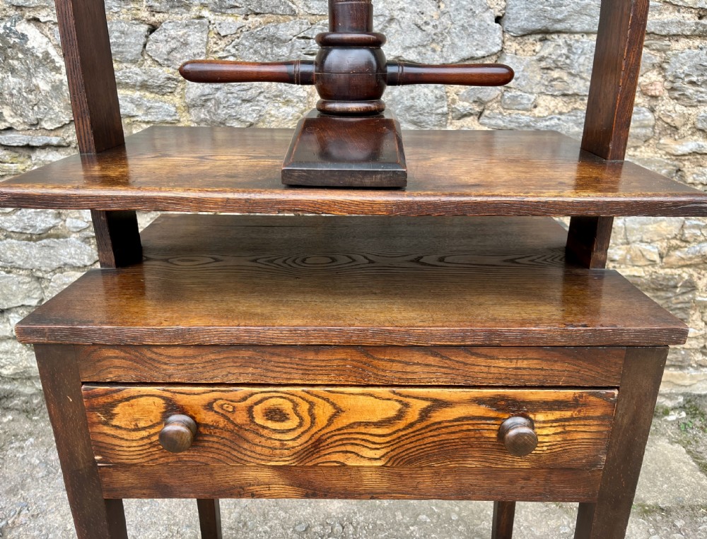An antique oak and elm book press table featuring a central turned wooden screw mechanism above a single drawer with two round knobs. View XV