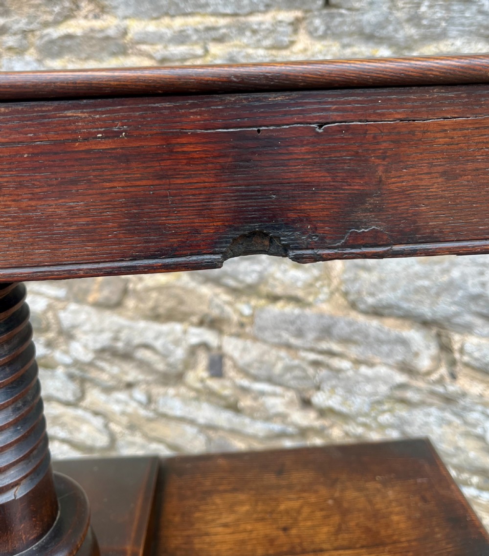 An antique oak and elm book press table featuring a central turned wooden screw mechanism above a single drawer with two round knobs. View XVII