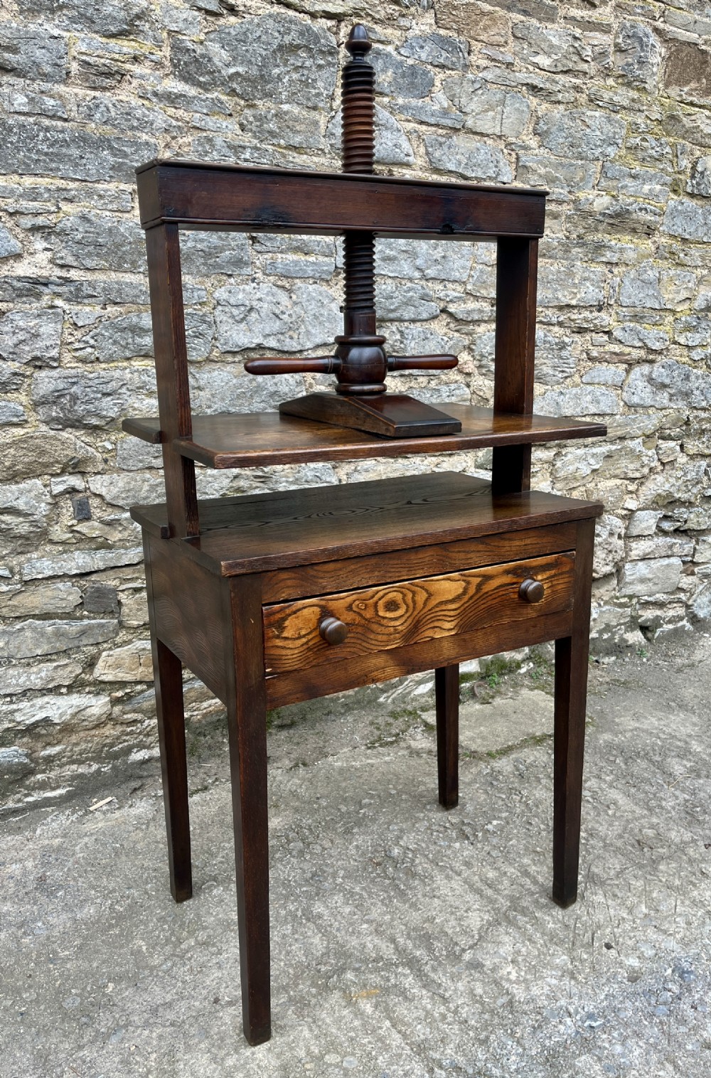 An antique oak and elm book press table featuring a central turned wooden screw mechanism above a single drawer with two round knobs. View XIX