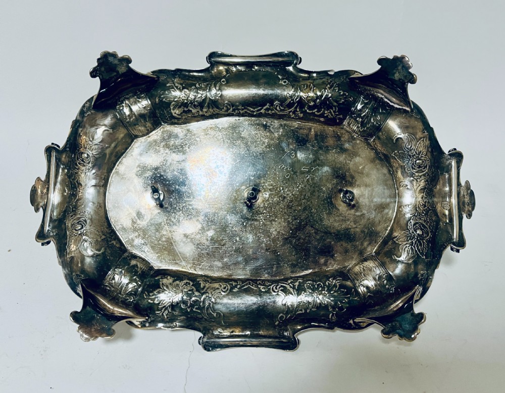 A Victorian silver-plated inkstand featuring an ornate tray with scrolled feet, two cut-glass inkwells in pierced holders, and a central taperstick. View XX