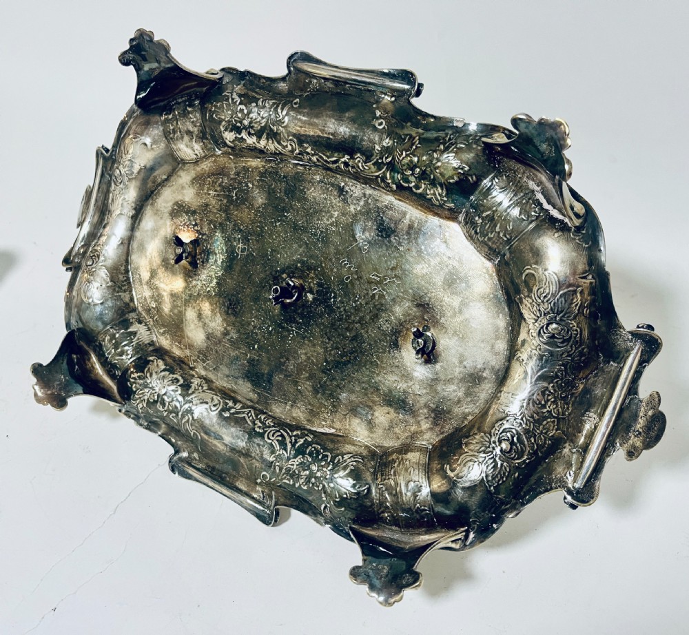 A Victorian silver-plated inkstand featuring an ornate tray with scrolled feet, two cut-glass inkwells in pierced holders, and a central taperstick. View XXI