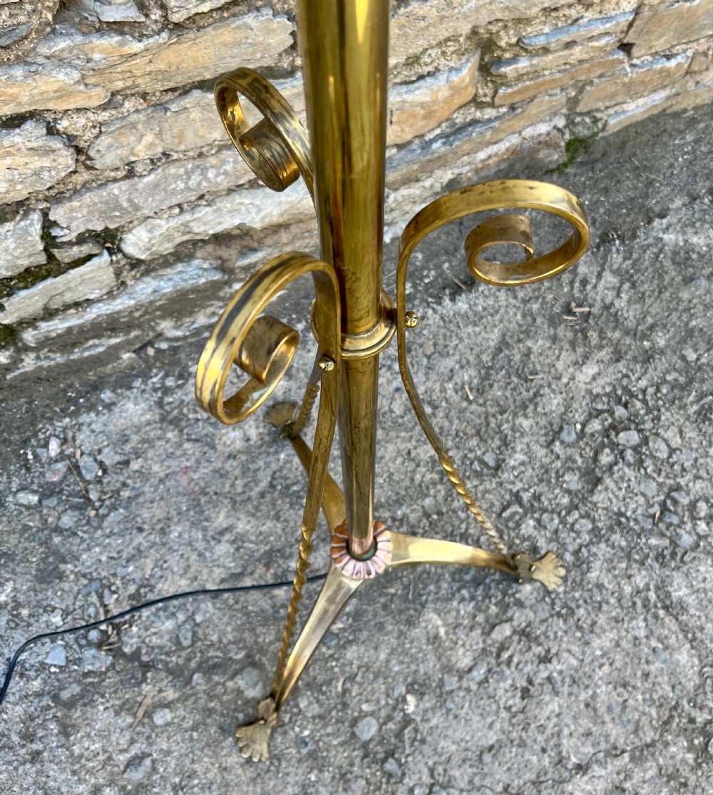 An antique brass telescopic standard lamp featuring tripod legs with scroll details and an adjustable vertical stem. View VII