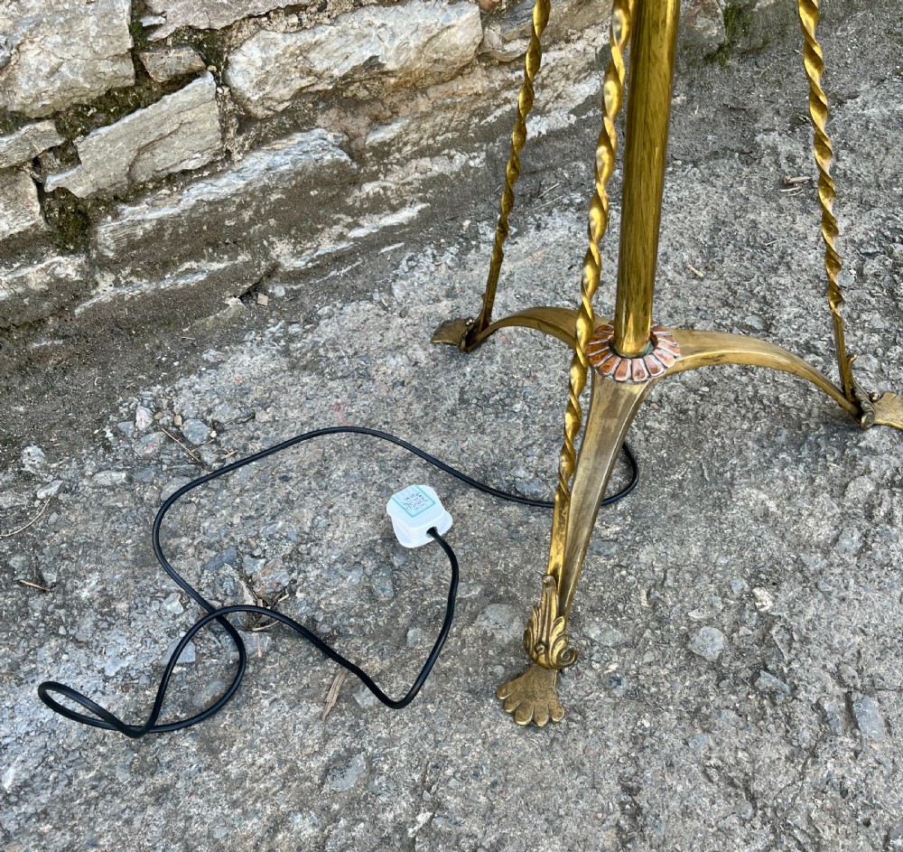 An antique brass telescopic standard lamp featuring tripod legs with scroll details and an adjustable vertical stem. View IX