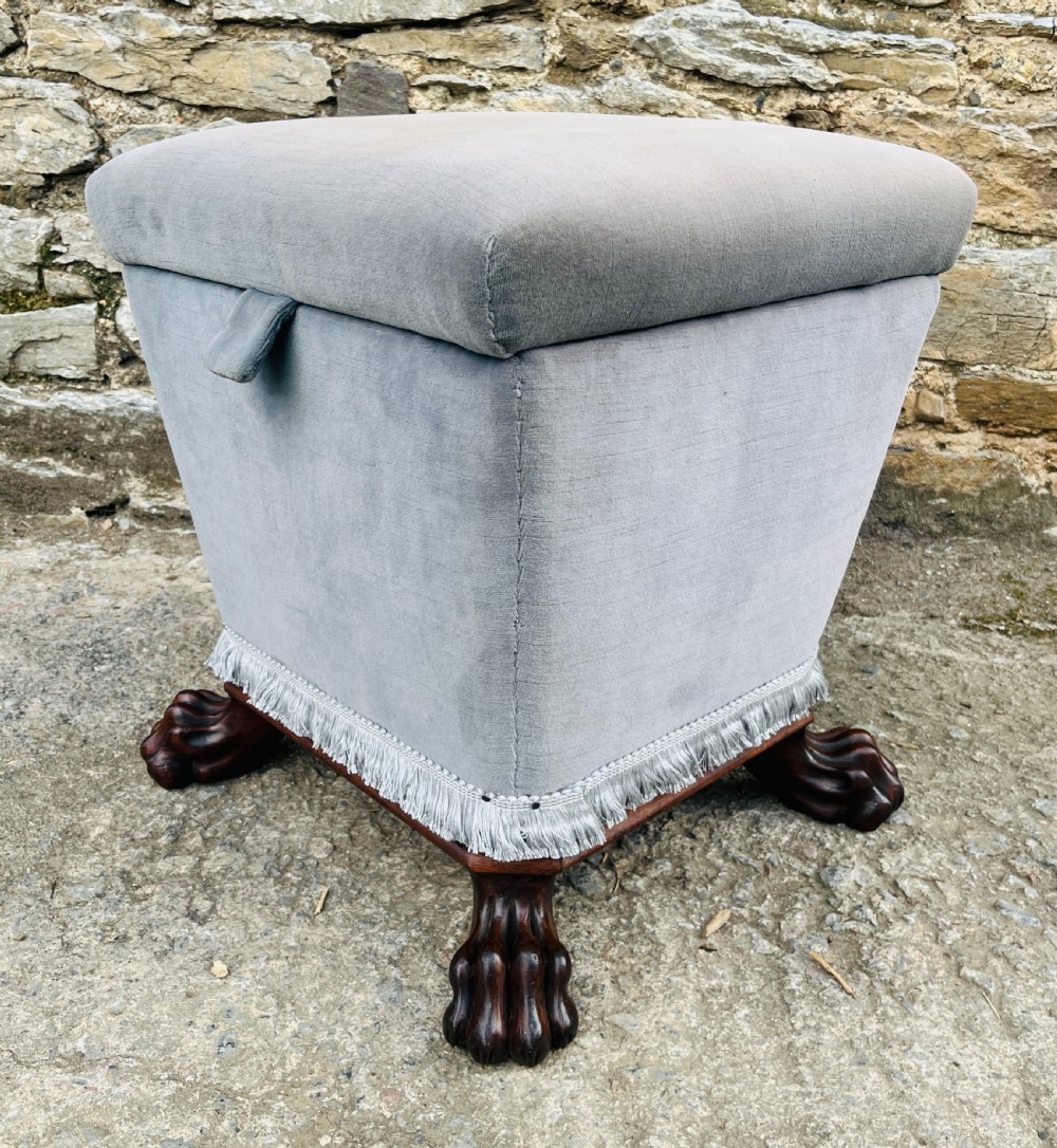 An upholstered grey velvet box ottoman featuring lower fringe trimming and dark mahogany carved lions paw feet. View VII