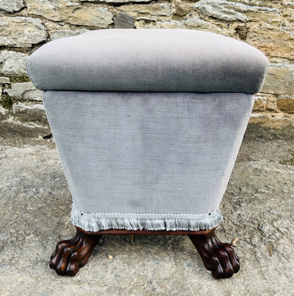 An upholstered grey velvet box ottoman featuring lower fringe trimming and dark mahogany carved lions paw feet. View VIII
