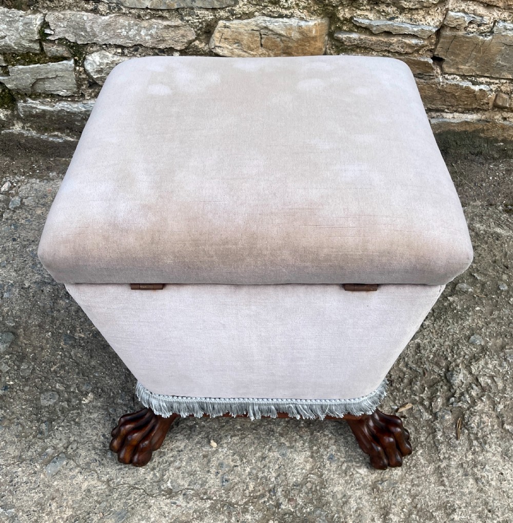 An upholstered grey velvet box ottoman featuring lower fringe trimming and dark mahogany carved lions paw feet. View IX