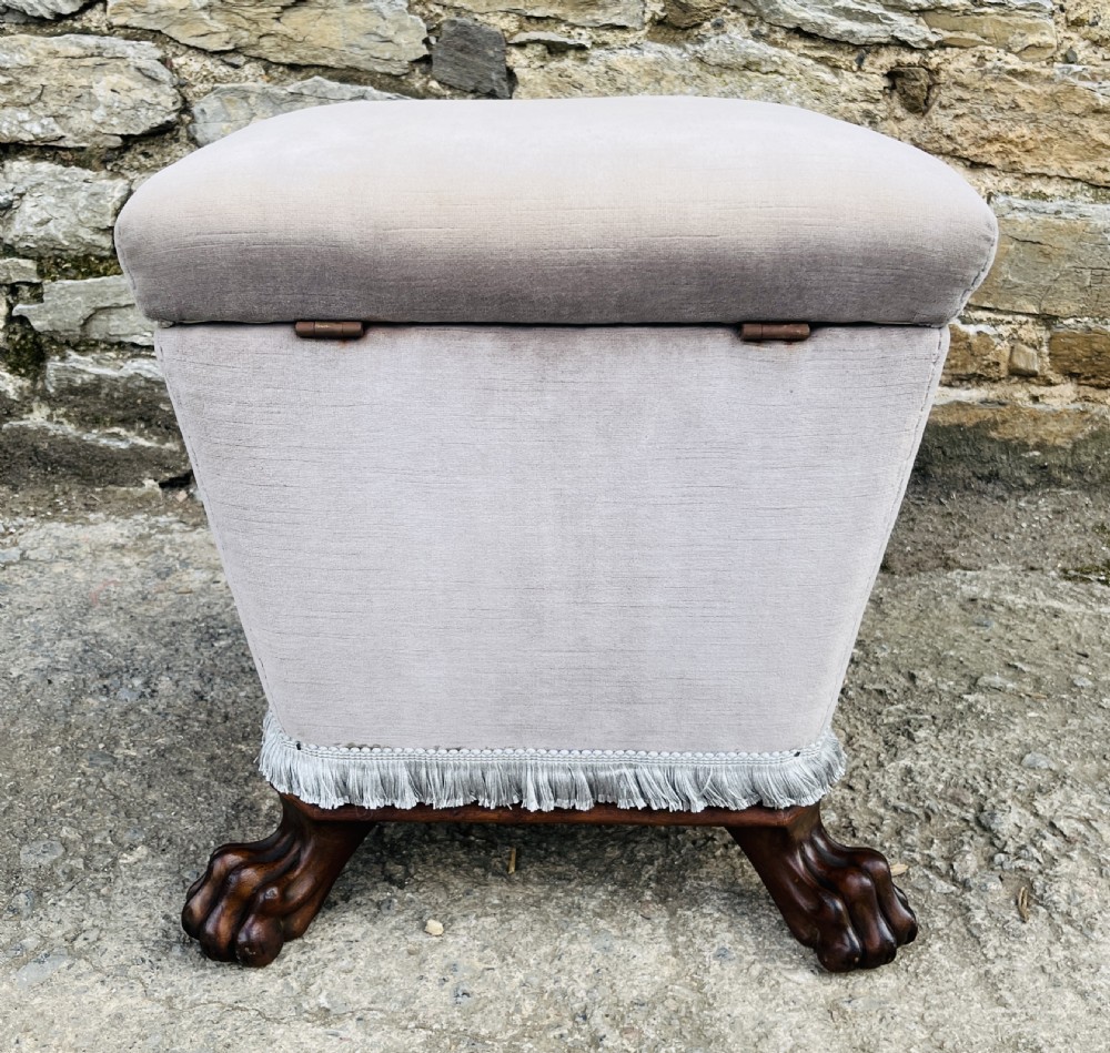 An upholstered grey velvet box ottoman featuring lower fringe trimming and dark mahogany carved lions paw feet. View XI