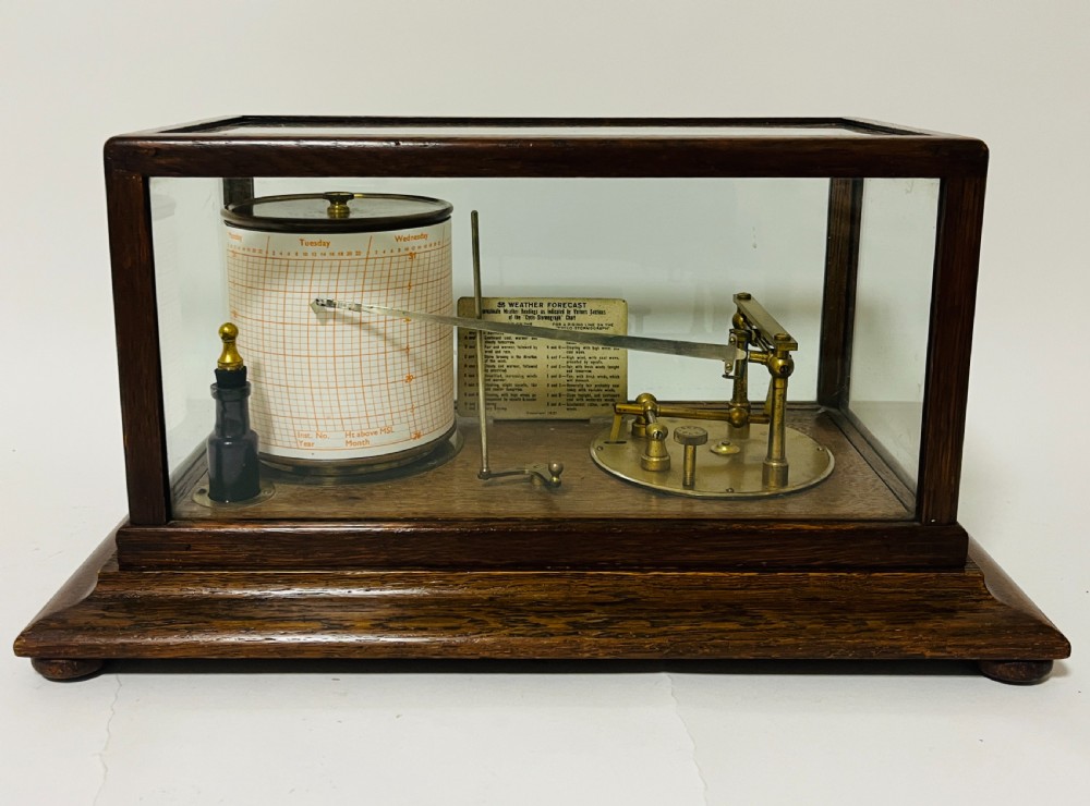 An antique barograph featuring an oak frame with glass side panels enclosing a revolving paper chart drum and polished brass mechanism. View II