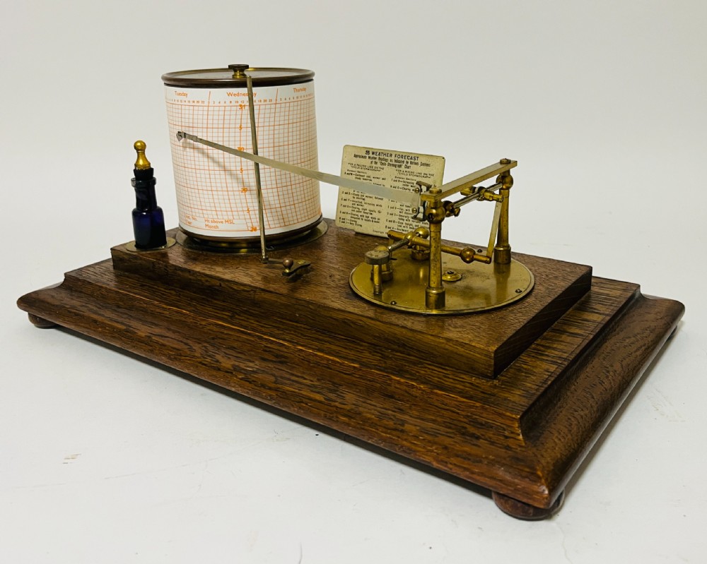 An antique barograph featuring an oak frame with glass side panels enclosing a revolving paper chart drum and polished brass mechanism. View VII