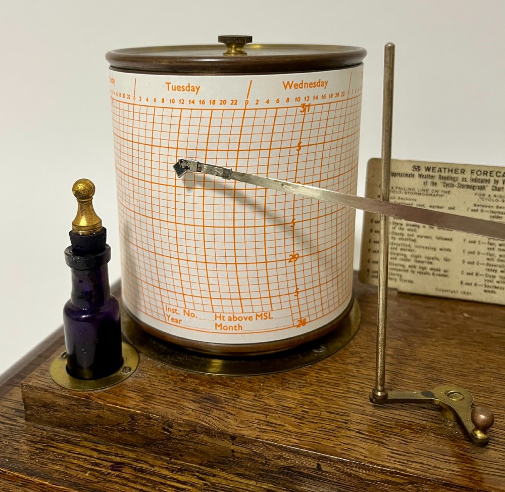 An antique barograph featuring an oak frame with glass side panels enclosing a revolving paper chart drum and polished brass mechanism. View VIII