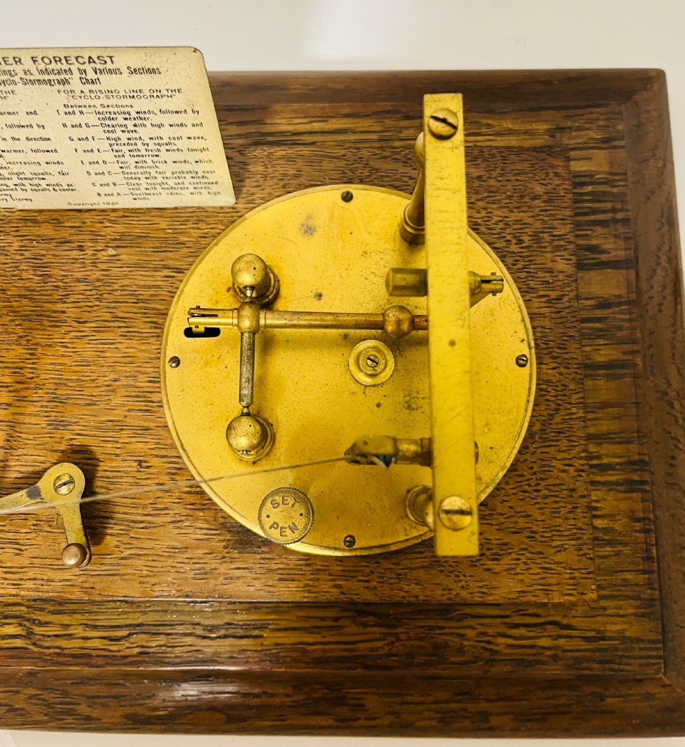 An antique barograph featuring an oak frame with glass side panels enclosing a revolving paper chart drum and polished brass mechanism. View XI