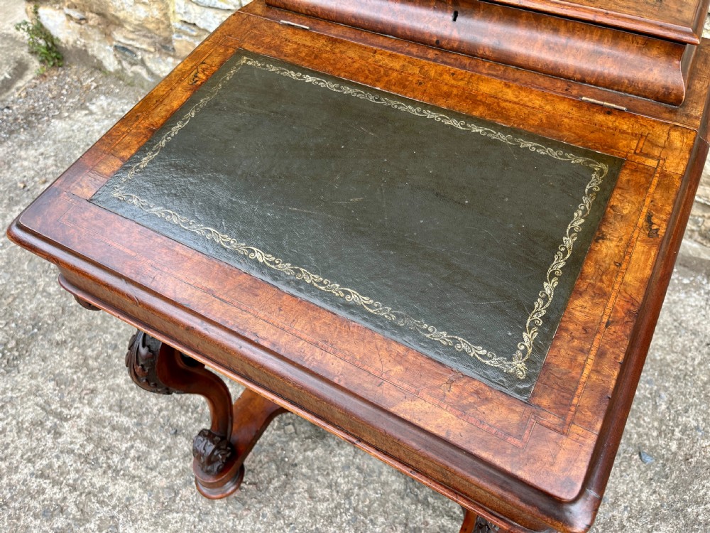 A Victorian burr walnut Davenport desk featuring a sloped writing top with a green leather insert and carved acanthus leaf front supports. View III