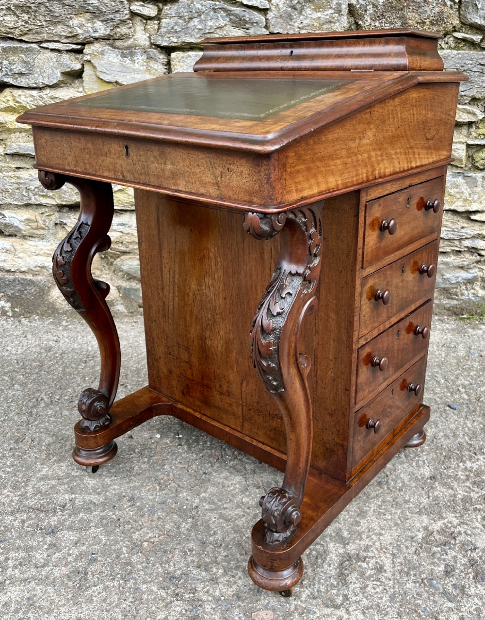 A Victorian burr walnut Davenport desk featuring a sloped writing top with a green leather insert and carved acanthus leaf front supports. View VI