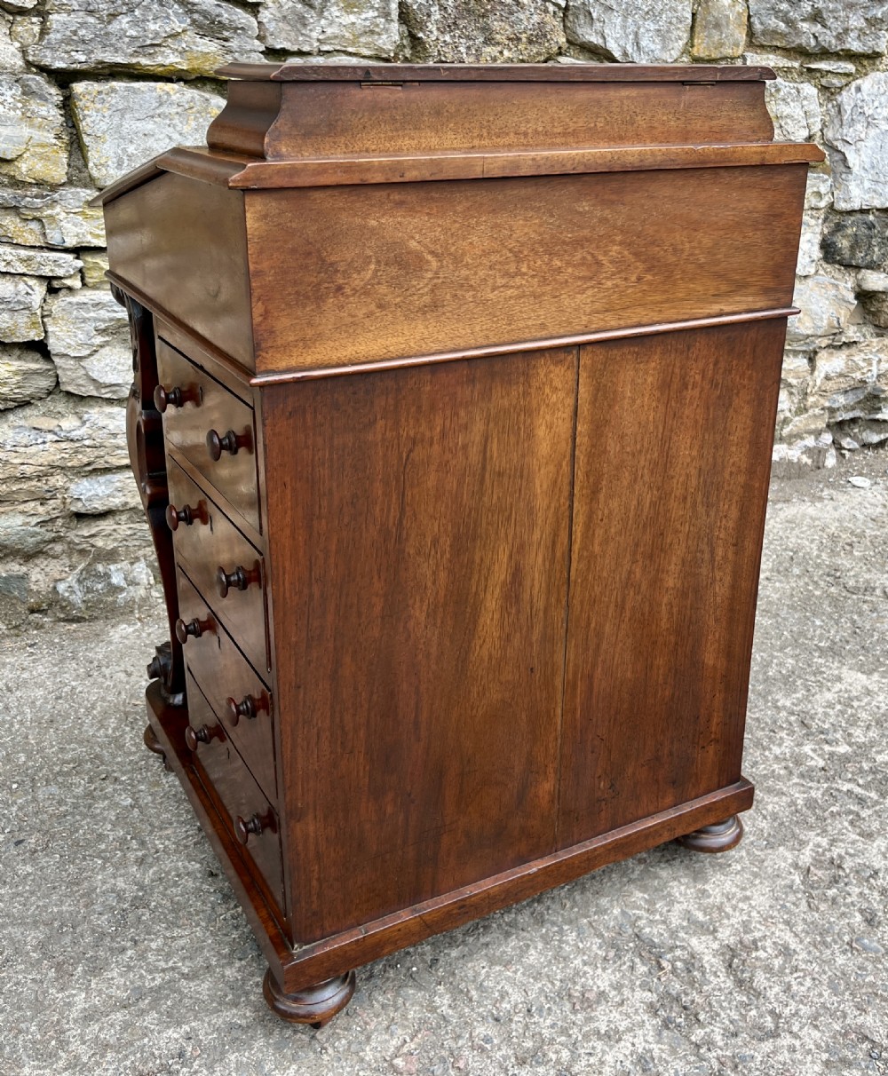 A Victorian burr walnut Davenport desk featuring a sloped writing top with a green leather insert and carved acanthus leaf front supports. View VIII