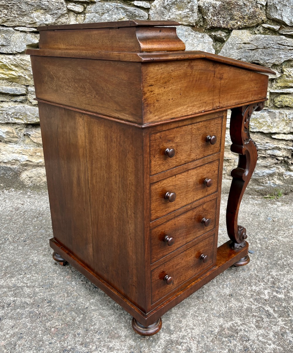 A Victorian burr walnut Davenport desk featuring a sloped writing top with a green leather insert and carved acanthus leaf front supports. View IX