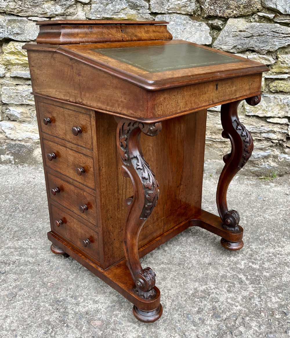 A Victorian burr walnut Davenport desk featuring a sloped writing top with a green leather insert and carved acanthus leaf front supports. View XII