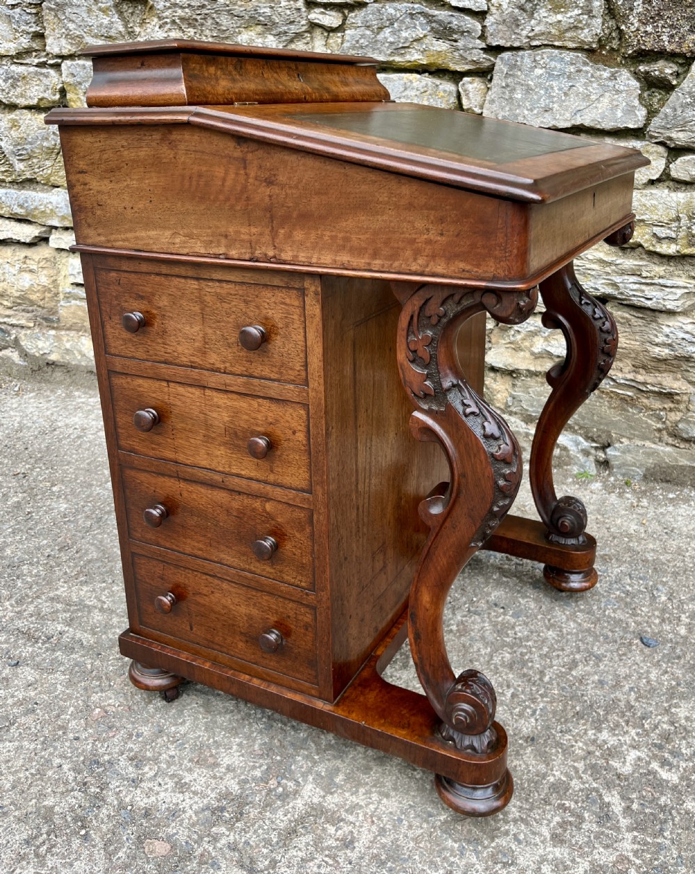 A Victorian burr walnut Davenport desk featuring a sloped writing top with a green leather insert and carved acanthus leaf front supports. View XIV