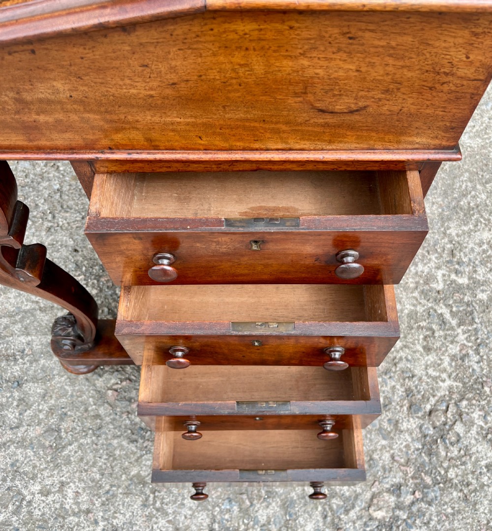 A Victorian burr walnut Davenport desk featuring a sloped writing top with a green leather insert and carved acanthus leaf front supports. View XVI
