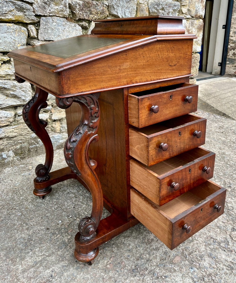 A Victorian burr walnut Davenport desk featuring a sloped writing top with a green leather insert and carved acanthus leaf front supports. View XVII