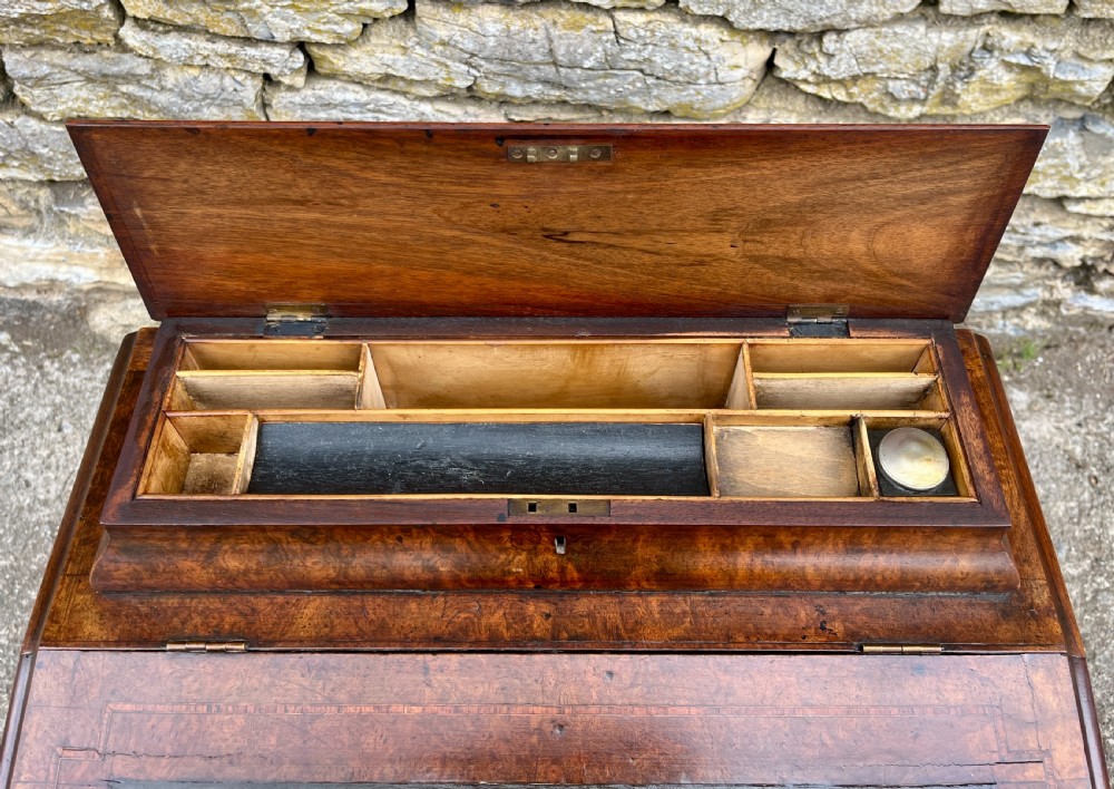 A Victorian burr walnut Davenport desk featuring a sloped writing top with a green leather insert and carved acanthus leaf front supports. View XX