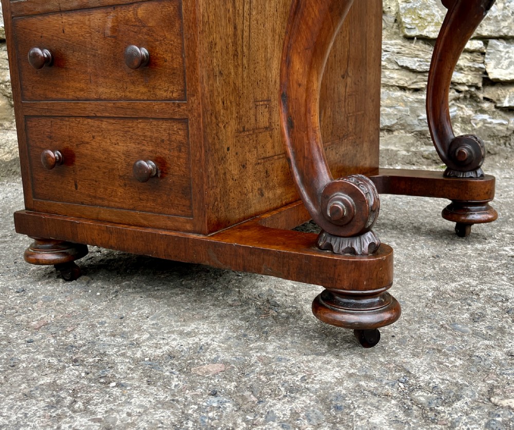 A Victorian burr walnut Davenport desk featuring a sloped writing top with a green leather insert and carved acanthus leaf front supports. View XXII