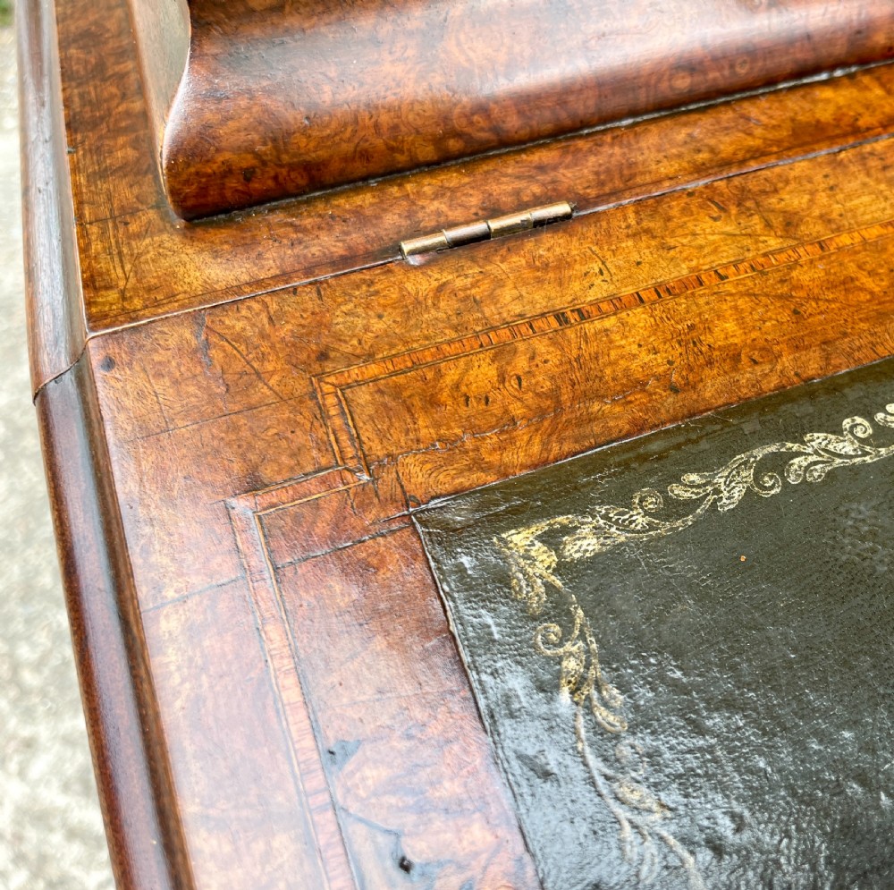 A Victorian burr walnut Davenport desk featuring a sloped writing top with a green leather insert and carved acanthus leaf front supports. View XXIV