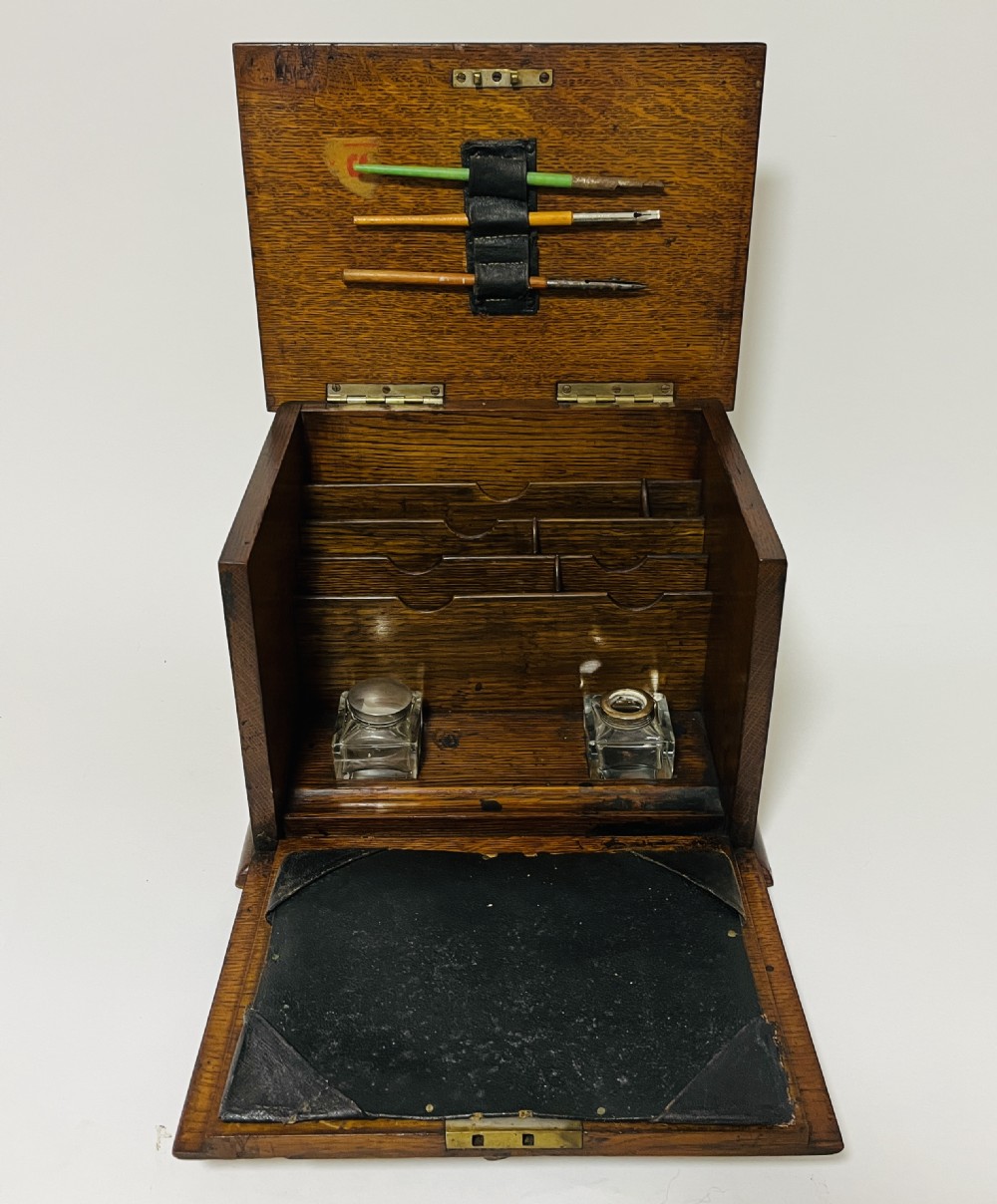 An antique oak stationery cabinet featuring a flush brass top handle, a brass keyhole with a key, and a hinged front panel. View II