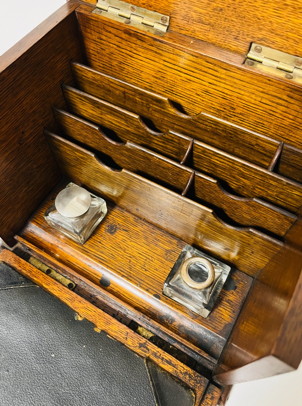 An antique oak stationery cabinet featuring a flush brass top handle, a brass keyhole with a key, and a hinged front panel. View III