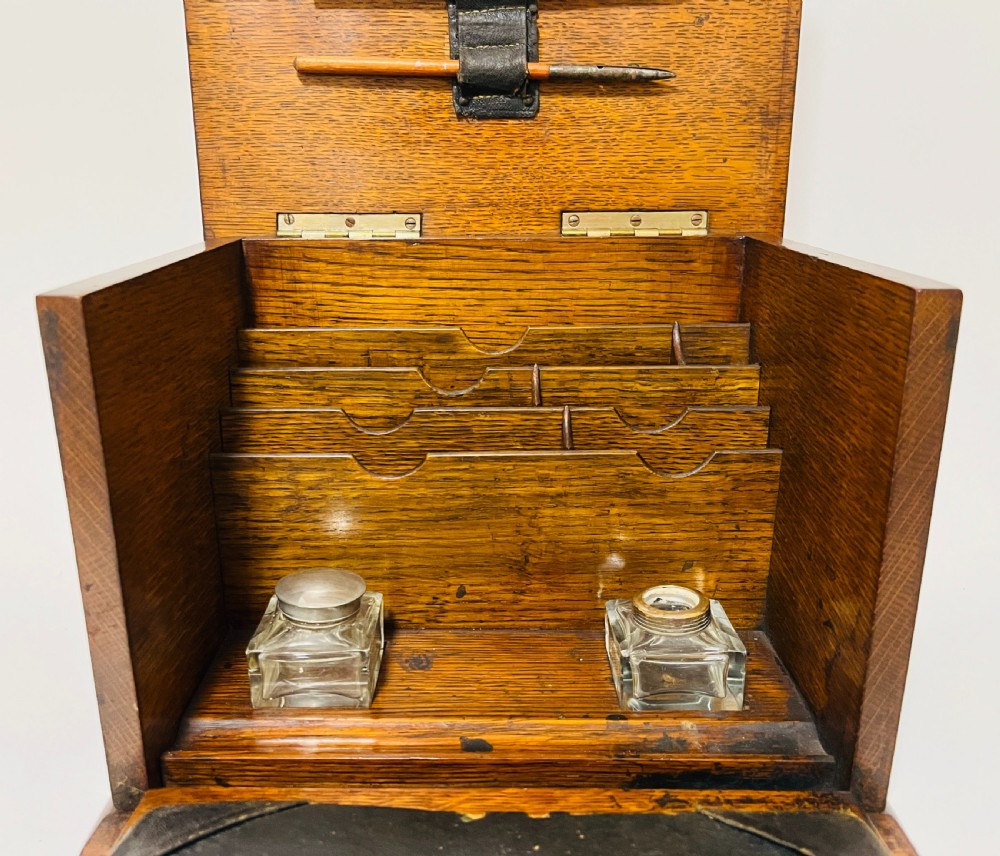 An antique oak stationery cabinet featuring a flush brass top handle, a brass keyhole with a key, and a hinged front panel. View V