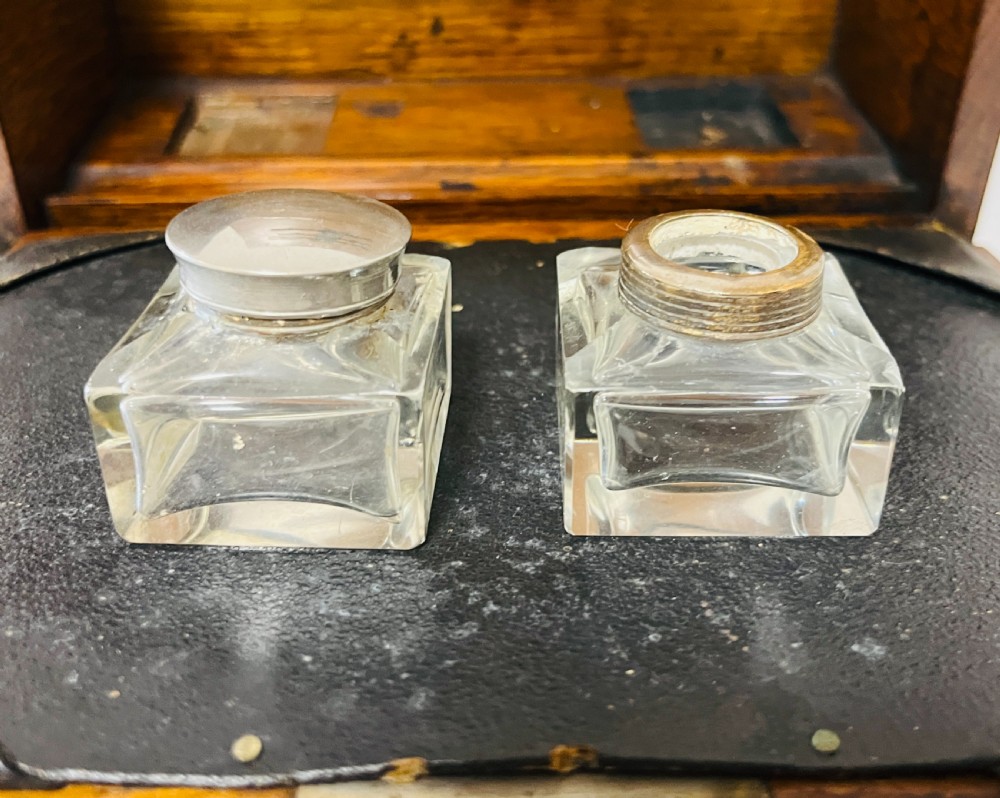 An antique oak stationery cabinet featuring a flush brass top handle, a brass keyhole with a key, and a hinged front panel. View VII