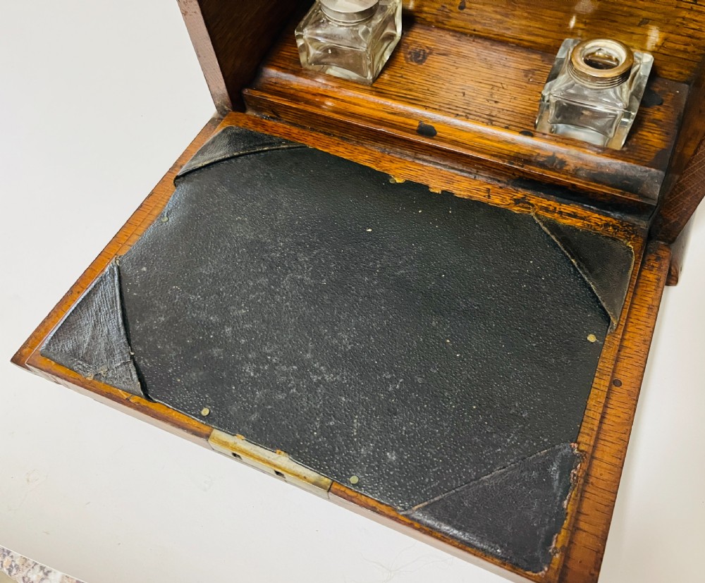 An antique oak stationery cabinet featuring a flush brass top handle, a brass keyhole with a key, and a hinged front panel. View VIII