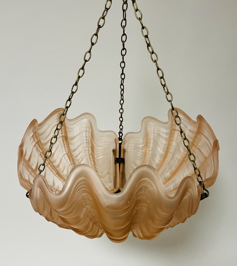 An Art Deco pink frosted glass clam shell ceiling pendant light suspended by three brass hanging chains. View II