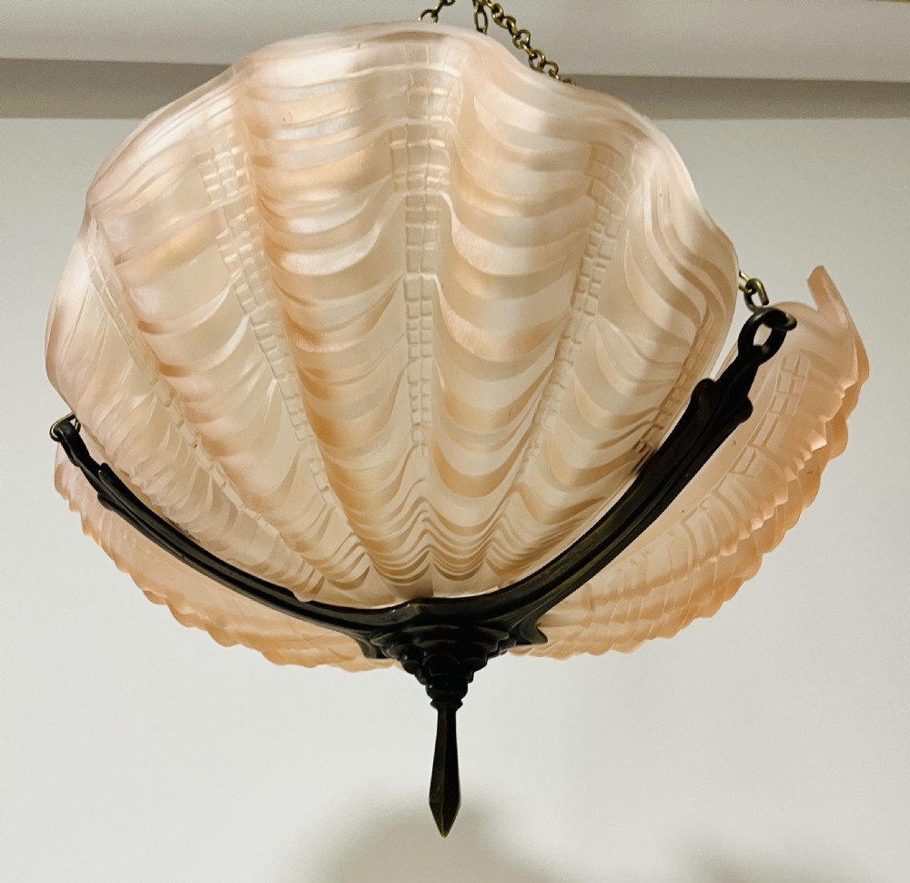 An Art Deco pink frosted glass clam shell ceiling pendant light suspended by three brass hanging chains. View X