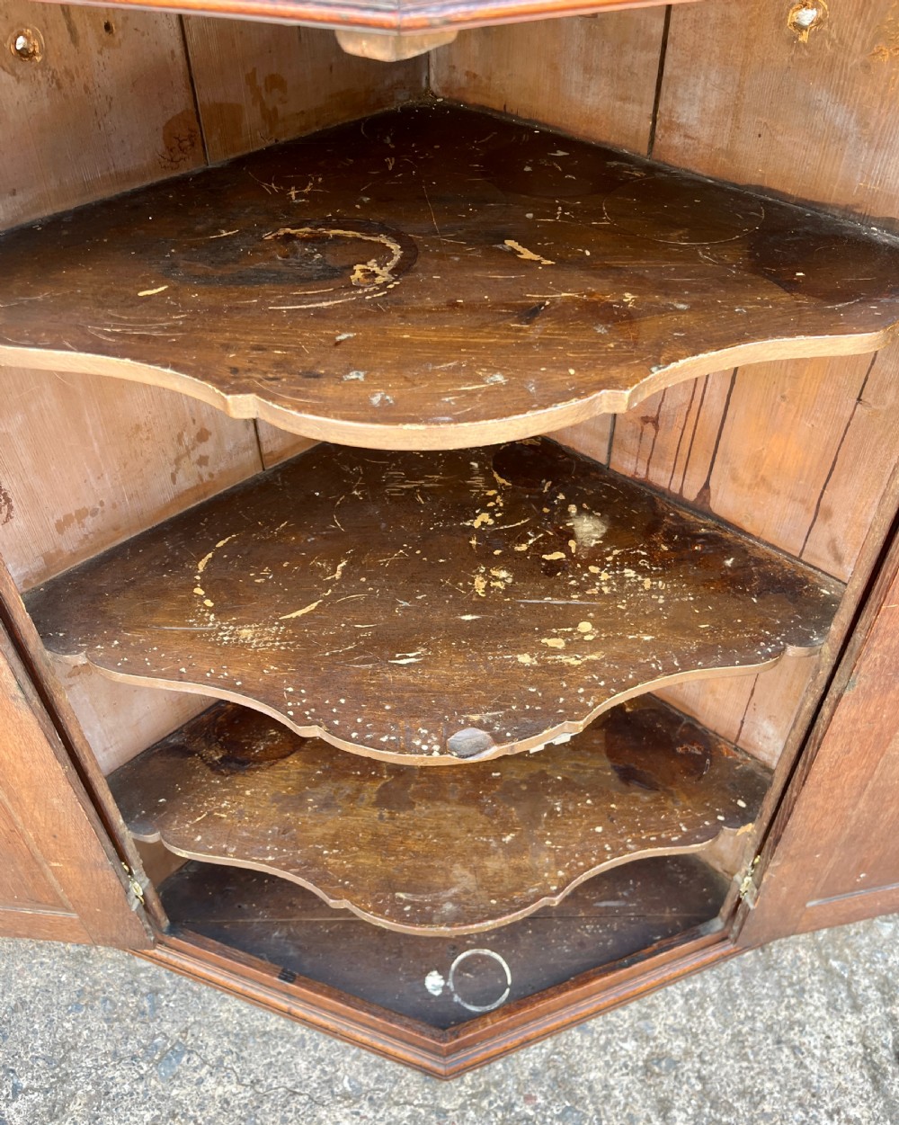 A Georgian dark oak wall-hanging corner cupboard featuring twin fielded panel doors and decorative brass H-hinges. View X