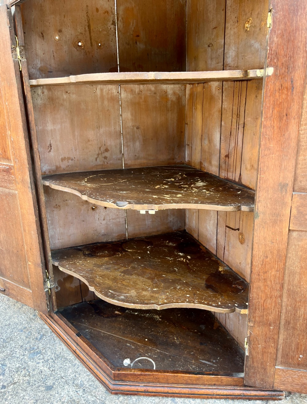 A Georgian dark oak wall-hanging corner cupboard featuring twin fielded panel doors and decorative brass H-hinges. View XI