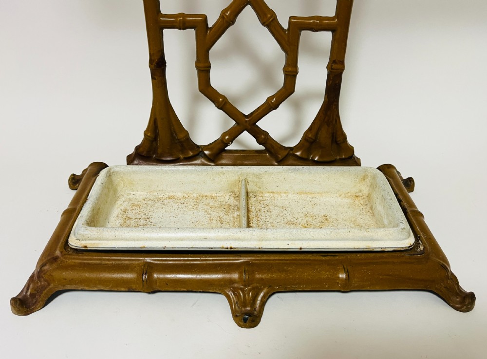 A Victorian cast iron faux bamboo umbrella stand in brown paint featuring geometric lattice backwork and a removable two-compartment drip tray. View II