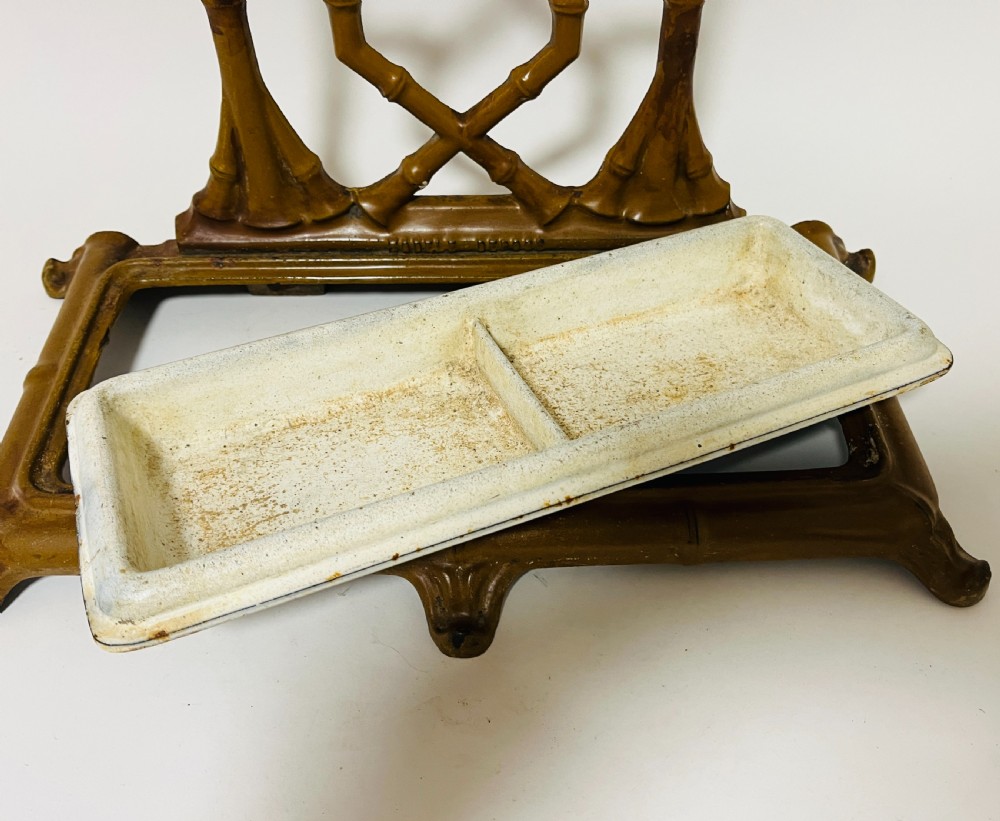 A Victorian cast iron faux bamboo umbrella stand in brown paint featuring geometric lattice backwork and a removable two-compartment drip tray. View III