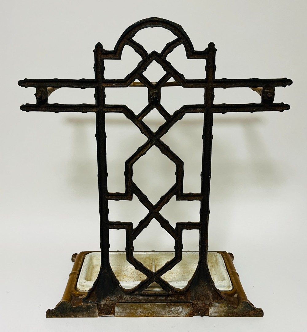 A Victorian cast iron faux bamboo umbrella stand in brown paint featuring geometric lattice backwork and a removable two-compartment drip tray. View VI