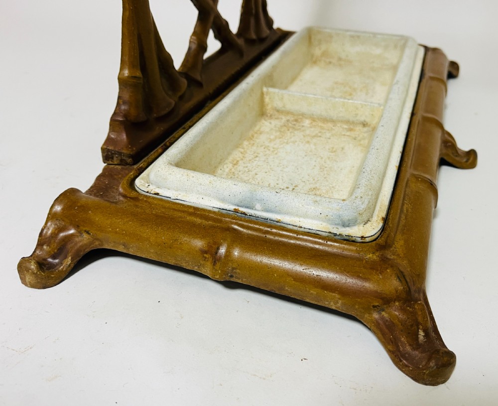 A Victorian cast iron faux bamboo umbrella stand in brown paint featuring geometric lattice backwork and a removable two-compartment drip tray. View VII