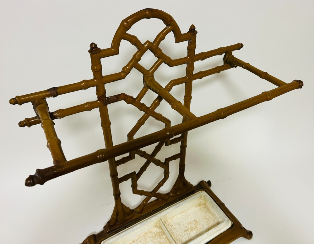 A Victorian cast iron faux bamboo umbrella stand in brown paint featuring geometric lattice backwork and a removable two-compartment drip tray. View VIII