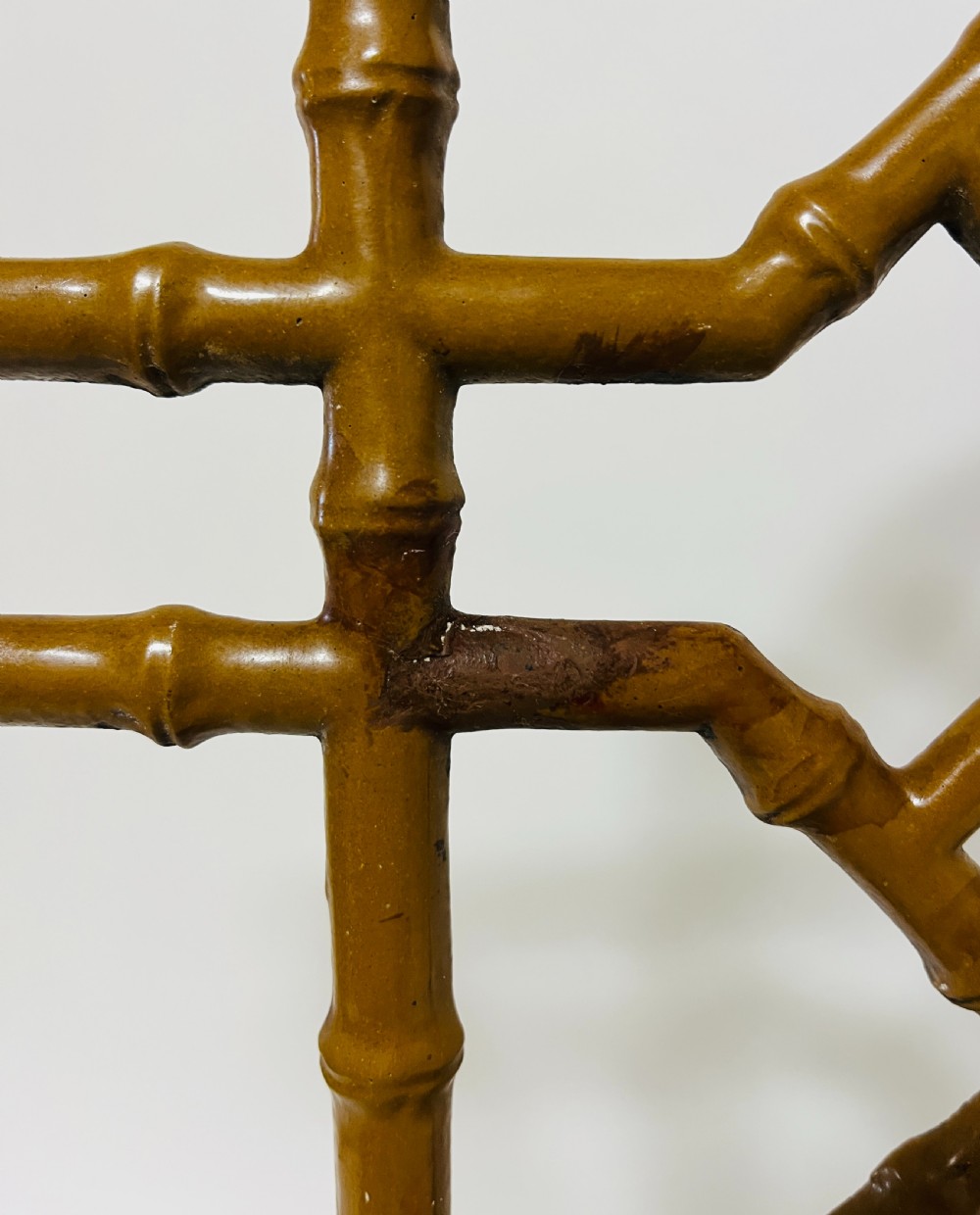 A Victorian cast iron faux bamboo umbrella stand in brown paint featuring geometric lattice backwork and a removable two-compartment drip tray. View X