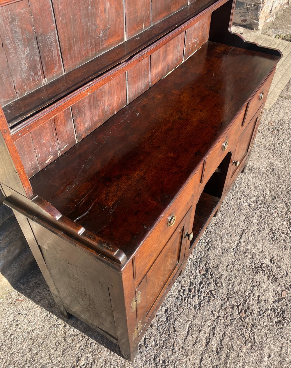 An antique dark oak Georgian dog kennel dresser featuring an open shelf rack above three drawers and two cupboard doors. View VI