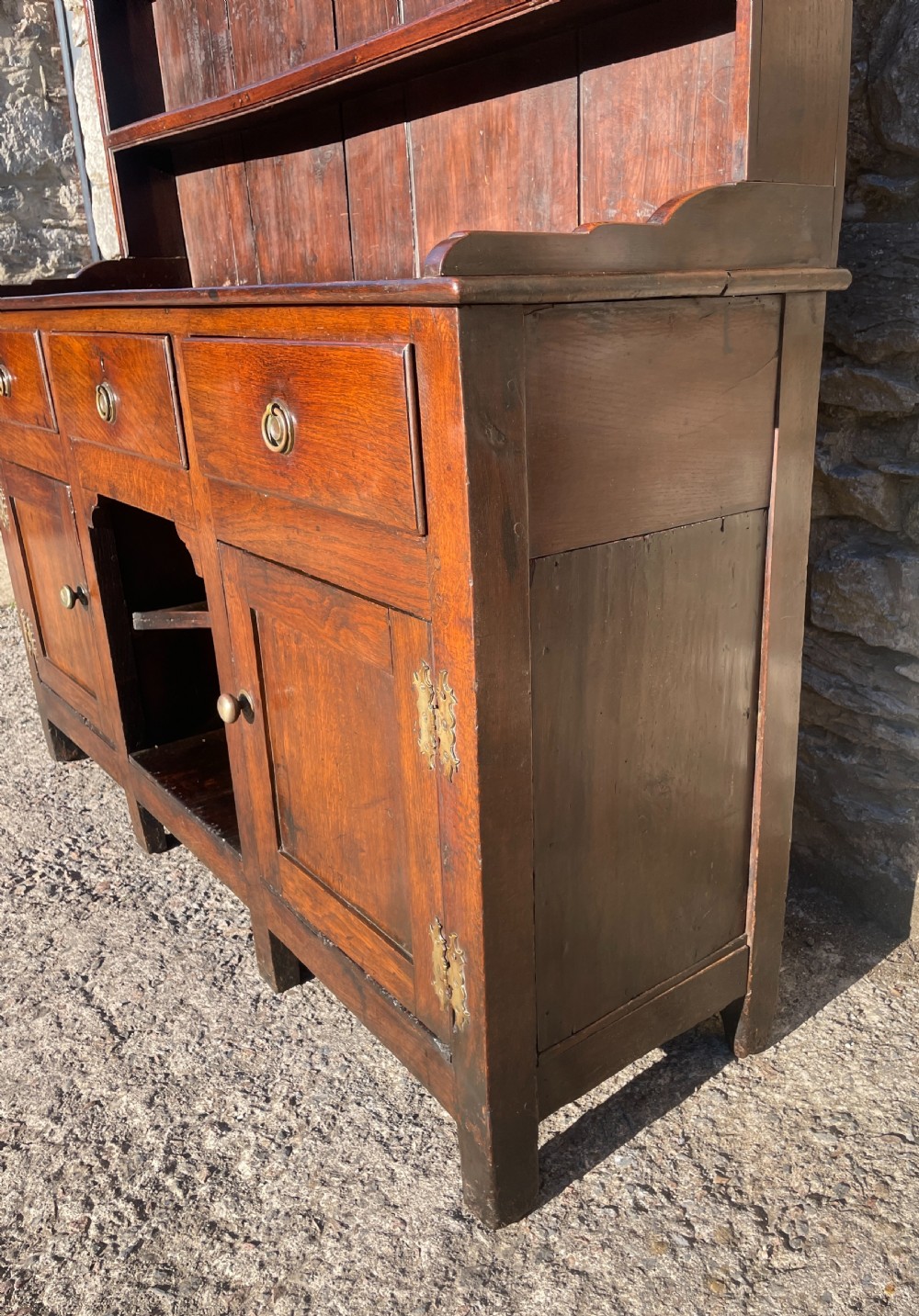An antique dark oak Georgian dog kennel dresser featuring an open shelf rack above three drawers and two cupboard doors. View VIII
